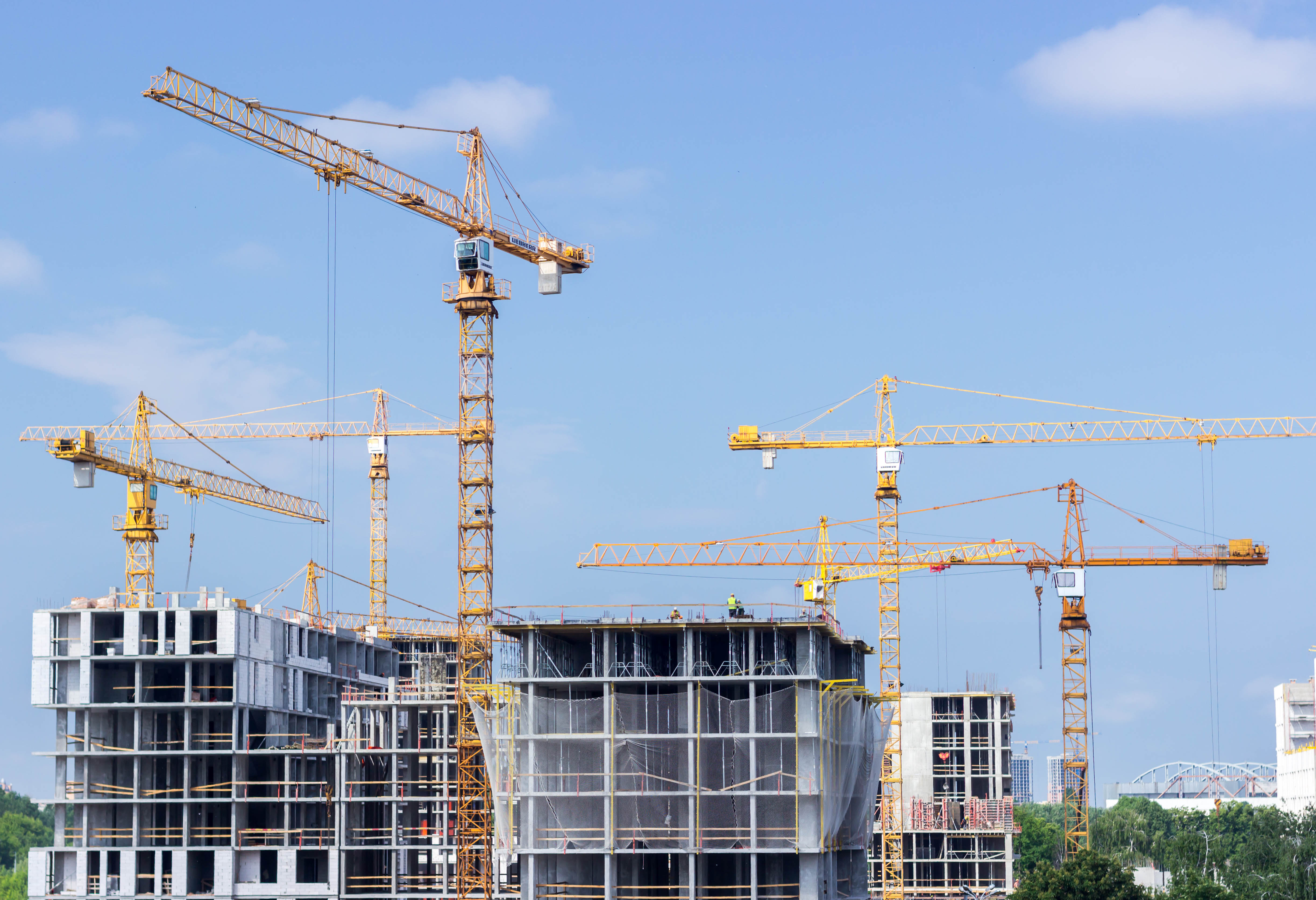 Buildings under construction with cranes and workers on the site.