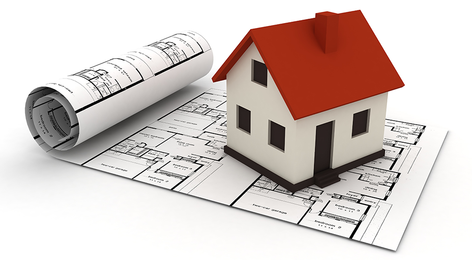 A toy house with a red roof sat on top of plans.
